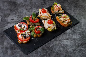 Assorted Crostini and Canap s on Slate Board Featuring Tomato, Cheese, Basil, and Seafood Toppings