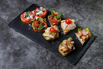 Assorted Crostini and Canap s on Slate Board Featuring Tomato, Cheese, Basil, and Seafood Toppings