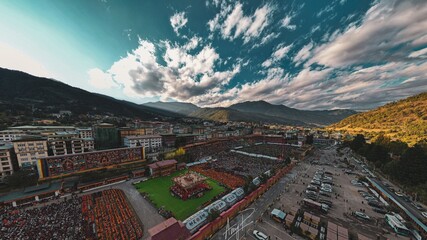 Aerial view of a lively celebration with vibrant colors contrasting against the muted urban landscape, framed by mountains, Thimphu, Thimphu, Bhutan.