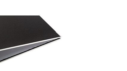 Black binder with a silver edge resting on a clean, white surface in a well-lit space with no distractions.