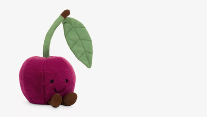 Cute plush cherry toy with smiling face and green leaf standing on white background.