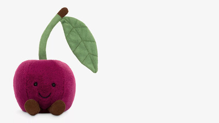 Cute plush cherry toy with smiling face and green leaf standing on white background.