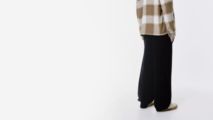 Fashionable outfit featuring oversized black pants and plaid shirt in minimalistic setting.