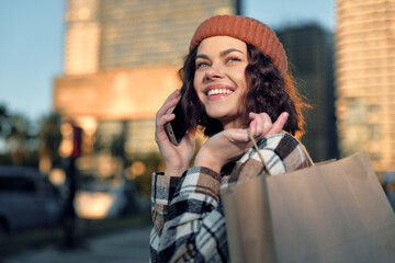 Fototapeta premium Woman shopping with phone and smile in city, candid lifestyle portrait showing authenticity and golden hour glow, mindful living moment of emotional storytelling and joyful connection.