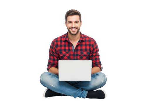 Smiling young man in a red plaid shirt and jeans sits cross legged on a black background holding a white laptop with a blank screen