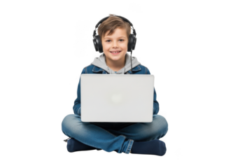 Joyful young boy with headphones sits cross legged on a black background happily holding a white laptop computer