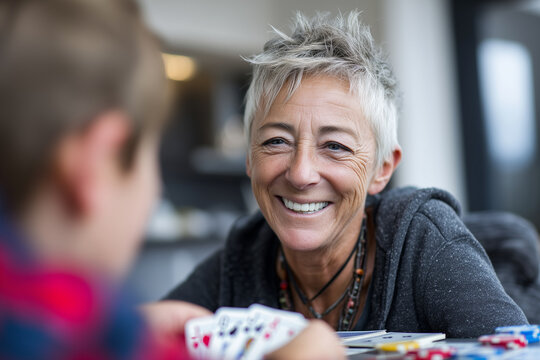 close-up older and younger friends playing cards at kitchen table, intergenerational bonding, - Powered by Adobe