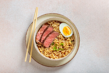 Bowl filled with ramen noodles, tender sliced beef, boiled egg and fresh green onions, asian style...