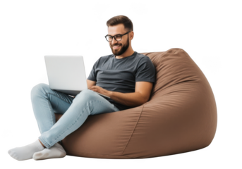 Young bearded man with glasses comfortably working on a laptop while sitting on a large brown bean bag chair