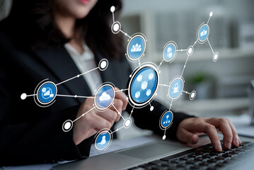 A businesswoman engages with a laptop while interacting with innovative technology icons in a modern office, emphasizing digital transformation and data analysis. Crux