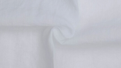 Soft white fabric draped elegantly on a smooth surface, showcasing its texture and subtle folds.