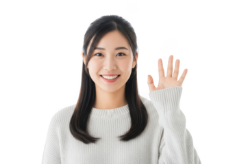 A young asian woman with long dark hair smiles warmly raising her hand in a friendly greeting against a stark black background
