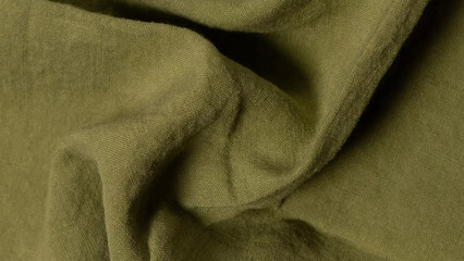 Textured green fabric draped elegantly showing soft folds and natural tones in light.