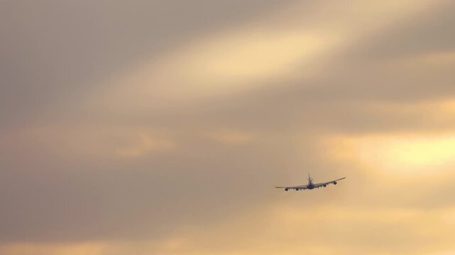 Wide-body four-engine aircraft ascending into the colorful sky during sunrise or sunset. Symbol of air travel and long-haul aviation.