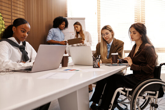 Inclusive diverse business team working together, woman in wheelchair at office meeting