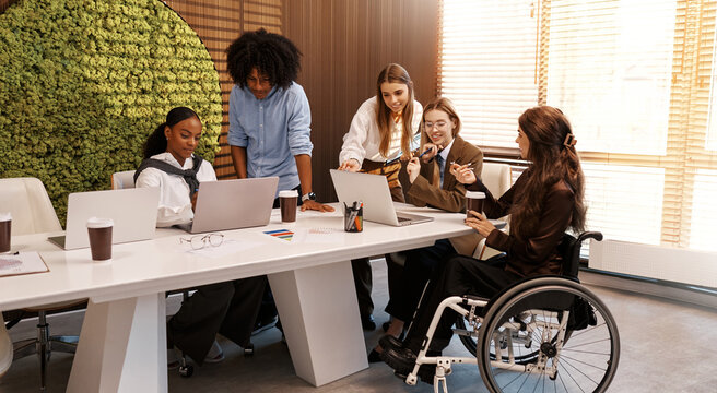 Inclusive diverse business team working together, woman in wheelchair at office meeting
