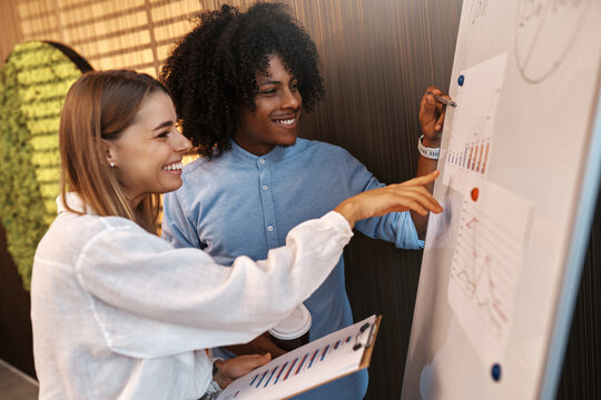 Coworkers discussing data charts on flipchart in modern office