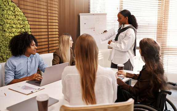 Businesswoman presenting graph to diverse team during office meeting
