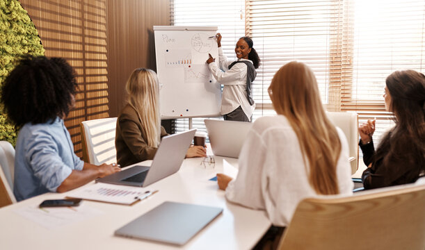 Businesswoman presenting graph to diverse team during office meeting - Powered by Adobe