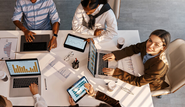 Diverse business team analyzing charts during office meeting from top view