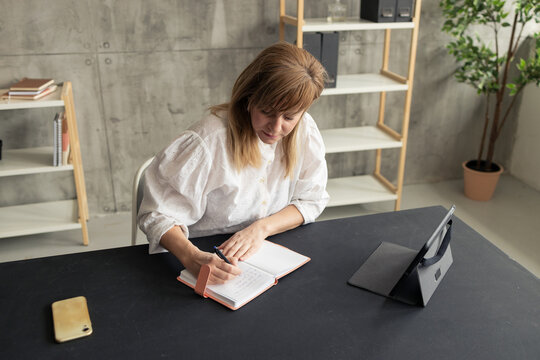 Focused businesswoman writing notes in notebook at office desk