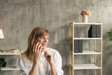 Happy businesswoman talking on phone in modern office