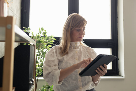 Businesswoman using digital tablet in modern office by window