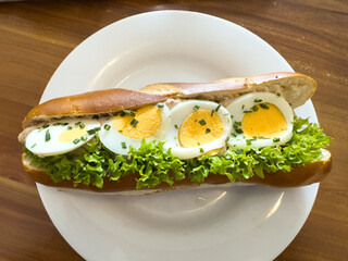 Fresh sandwich with boiled eggs, crisp lettuce, and creamy dressing served on a toasted bun, showcasing a delicious and healthy meal option for food lovers