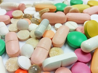 Macro close-up of assorted colorful pills, tablets, capsules, and vitamins scattered on a clean...