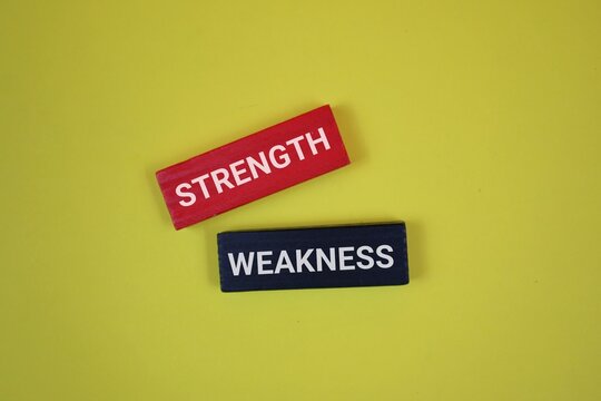 Two blocks labeled Strength and Weakness rest on an yellow backdrop. Ideal for articles on self-improvement, teamwork, and decision making.