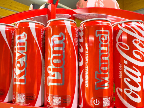  Coca-Cola cans featuring personalized names Kevin, Liam, and Manuel on a vibrant red display, showcasing the brand's unique marketing strategy and consumer engagement