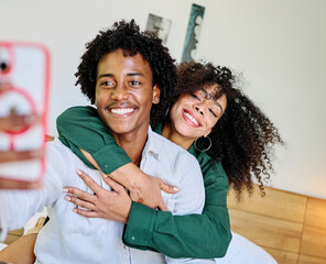 Portrait of a young happy couple having fun taking a selfie with camera on smartphone in bed at home. Girlfriend and boyfriend bonding, love concept