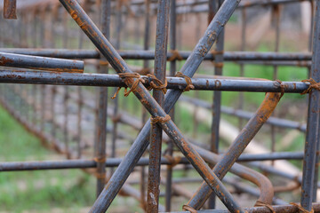A close-up view of a rust-textured steel rebar frame used for house foundation construction, tightly tied with wire to form a strong structural grid.
