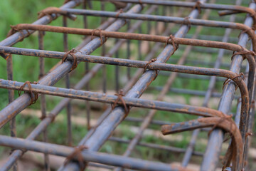 A close-up view of a rust-textured steel rebar frame used for house foundation construction, tightly tied with wire to form a strong structural grid.