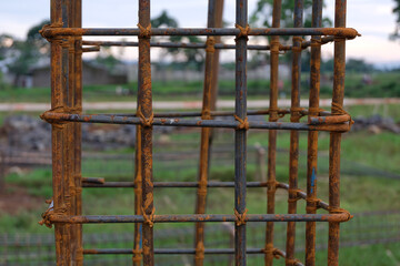 A close-up view of a rust-textured steel rebar frame used for house foundation construction, tightly tied with wire to form a strong structural grid.