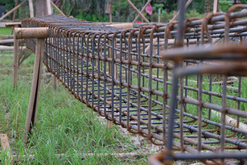 A close-up shot of a reinforced steel rebar frame used for residential building construction. The metal bars are tightly tied with wire, forming a strong grid structure with visible rust textures
