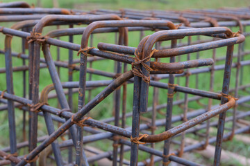 A close-up view of a rust-textured steel rebar frame used for house foundation construction, tightly tied with wire to form a strong structural grid.