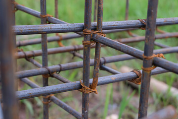 A close-up view of a rust-textured steel rebar frame used for house foundation construction, tightly tied with wire to form a strong structural grid.