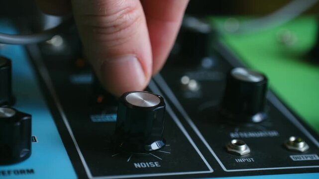 accurate sound adjustment, skilled hand precisely calibrates electronic sound devices, meticulous hand movements carefully involve adjusting and aligning electronic sound controls accurately