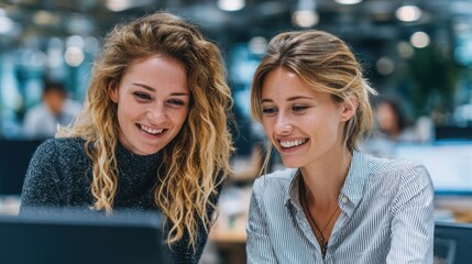 Two smiling female colleagues collaborating on a project in the office, fostering teamwork and success in business