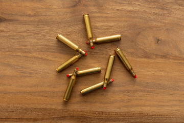 Arrangement of cartridges fanned across a wooden tabletop photographed from above to emphasize brass tones, repetition and conceptual tension between object pattern and thematic meaning.
