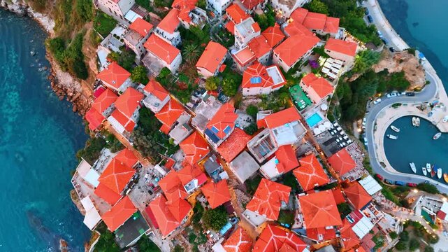 Going up over the red roofs of the buildings covering the rocky shore. Aerial perspective on the beautiful marina and sea resort in Montenegro.