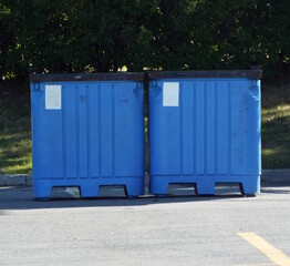 A close-up of two identical, large, bright blue collection bins.
