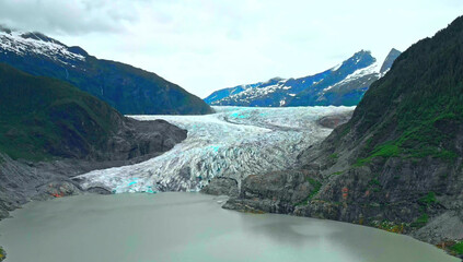 Obraz premium Massive Glacier Flowing into a Lake Between Steep Mountains