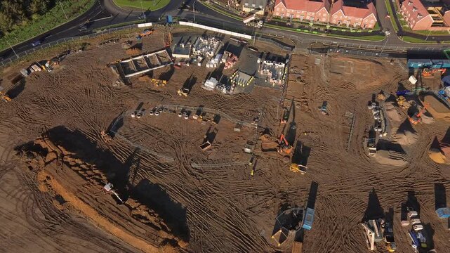 Aerial drone video of a large housing construction site with machinery, foundations, and materials being prepared for new residential development. 