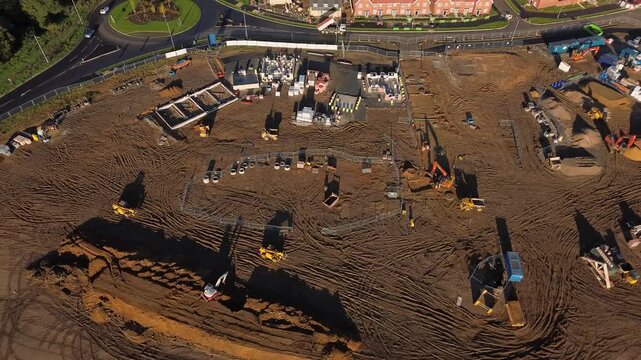 Aerial drone video of a large housing construction site with machinery, foundations, and materials being prepared for new residential development. 