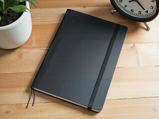 Black notebook mockup, in black and wood tones, for professional branding [with copy space]