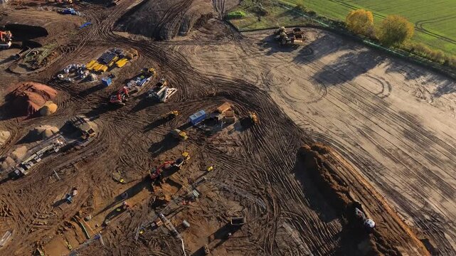Aerial drone video of a large housing construction site with machinery, foundations, and materials being prepared for new residential development. 