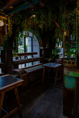 Obraz premium Atmospheric industrial-style café corner in Tel Aviv, Israel, featuring rustic metal elements, hanging greenery, wooden tables, and a moody urban interior design perfect for background or life style