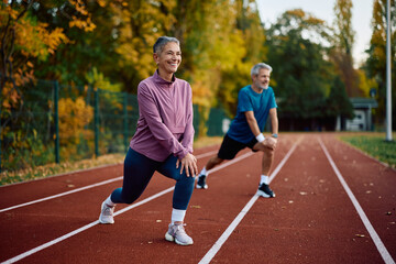 Obraz premium Mature athletes stretching their legs while warming up for sports training outdoors.